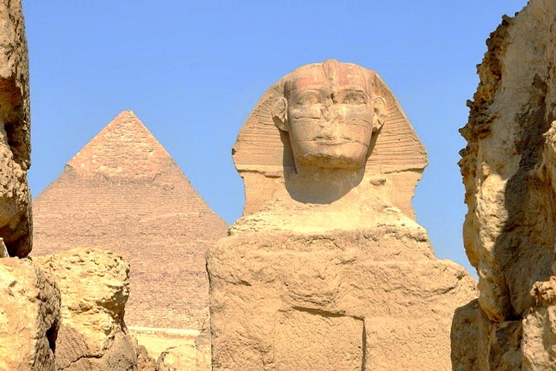 Великий Сфинкс Гизы — древнейшая грандиозная монолитная статуя. Но ни точный возраст, ни его строители не известны. По мнению ученых, он построен египтянами Древнего царства во время правления фараона Хафрена в XXVI веке до нашей эры. Однако несколько свидетельств указывают на то, что Сфинкс намного старше и построен кем-то, кроме египтян. В 1857 году Огюст Мариетт, основатель египетского музея в Каире, преуспел в переводе надписей на обелиске, высеченном из известняковой глыбы в VII века до нашей эры. В нем подробно рассказывается о том, как фараон Хеопс наткнулся на Сфинкса, который в то время был погребенным в песке в течение тысяч лет, а Хеопс только раскопал и восстановил памятник. Профессор и геолог Бостонского университета доктор Роберт Шох проанализировал Сфинкса и пришел к выводу, что модели выветривания на его поверхности были не результатом ветра, а следствием сильных ливней. В соседних пирамидах нет таких признаков эрозии, но они были построены примерно в тот же период, что и Сфинкс. Это заставило некоторых поверить, что статуя присутствовала в районе задолго до 2500 г. до н.э., так как эти места испытывали засуху в течение последних 5000 лет. Существует теория, что Нил соответствует Млечному Пути, а Великие Пирамиды положению звезд в созвездии Ориона. Согласно ей, массивная скульптура Сфинкса ориентирована на созвездие Льва, и появилась она в 10 500 году до нашей эры. Действительно, в то время плато Гиза получало гораздо больше осадков, чем 4500 лет назад. Роберт Шох полагает, что фараон Хафрен просто восстановил Сфинкса, чтобы включить его в свой погребальный комплекс. По мнению профессора, нынешняя голова не могла быть оригинальной, потому что ее эрозия не совпадает с разрушениями остальной части статуи. Если египтяне не строили Сфинкса, то кто это сделал, и что с ними случилось? Тайна вокруг него углубляется. По словам мистика Эдгара Кейси, это были атланты. Под колоссальным строением они возвели секретную комнату под названием Зал Летописи, в которой содержались знания и мудрость давно утраченной цивилизации. Многие люди искали эти помещения, а недавний проникающий радиолокационный анализ статуи доказал существование полостей под Сфинксом. Они вполне могли быть скрытыми комнатами, но археологические раскопки официально запрещены. Некоторые теоретики считают, что комната уже найдена, а ее содержимое изучается избранными людьми и хранится в тайне от остального мира. Говорят, что истина будет наносить ущерб нынешнему миропорядку, и общество еще не готово принять тот факт, что мы не являемся первой технологически развитой цивилизацией, населяющей Землю.